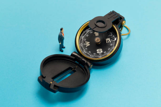 istock Miniature businessman and compass on blue background 1268387591
