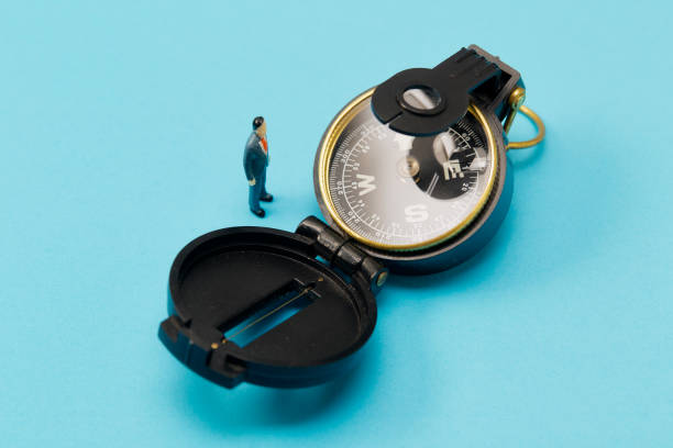 istock Miniature businessman and compass on blue background 1268387593