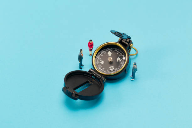 istock Miniature businessman and compass on blue background 1268387602