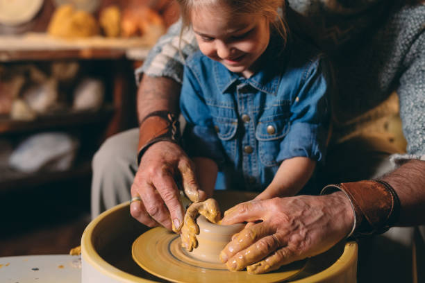 istock Pottery workshop. Grandpa teaches granddaughter pottery. Clay modeling 1268389096