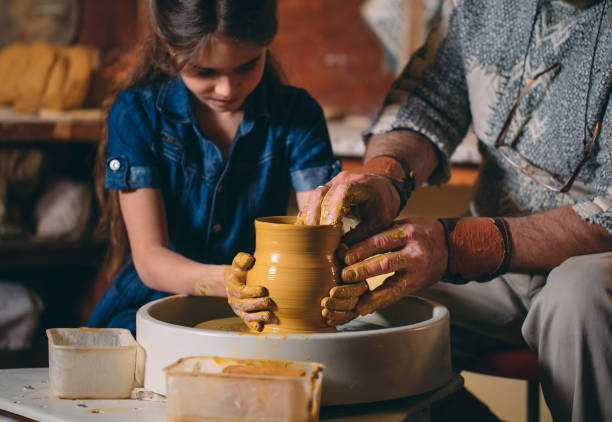 istock Pottery workshop. Grandpa teaches granddaughter pottery. Clay modeling 1268389233