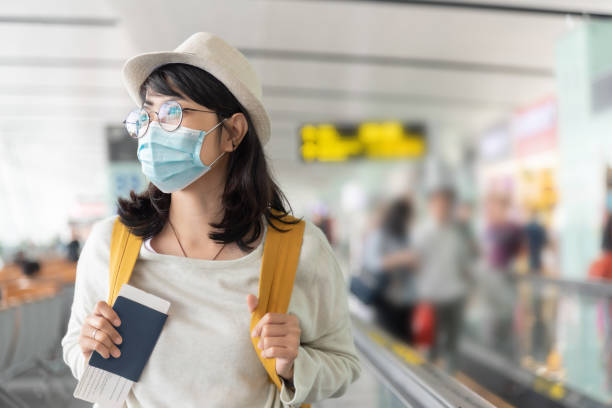donna asiatica che indossa una maschera protettiva per il viso nell'aeroporto internazionale. - safety protective workwear healthcare and medicine healthy lifestyle foto e immagini stock
