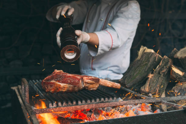 Chef pepper the steak on a fire.