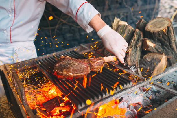 istock Chef Cooking steak. Cook turns the meat on the fire. 1268389403