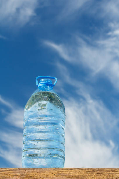 istock Big water bottle on wooden board with blue sky on background 1268392411