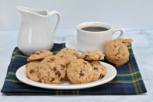 Granola chocolate chip cookies on a plate.  Coffee in background.  Macro with copy space.