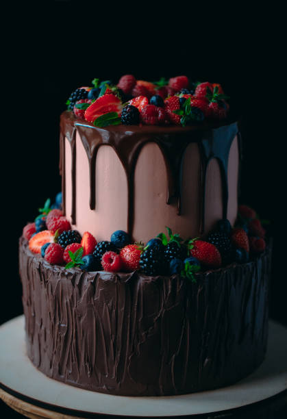 istock Fruit chocolate cake on wooden stand on black background. 1268392605