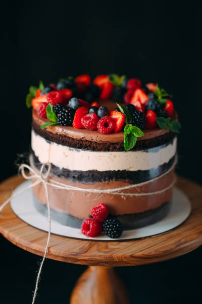 istock Fruit cake. Cake decorated with berries on a wooden stand on a black background. 1268392665