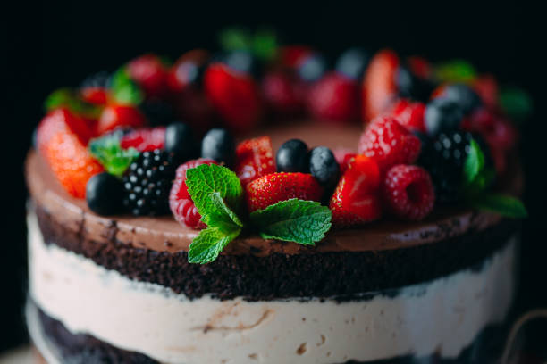 istock Fruit cake. Cake decorated with berries on a wooden stand on a black background. 1268392695