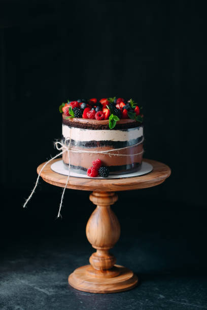 istock Fruit cake. Cake decorated with berries on a wooden stand on a black background. 1268392789