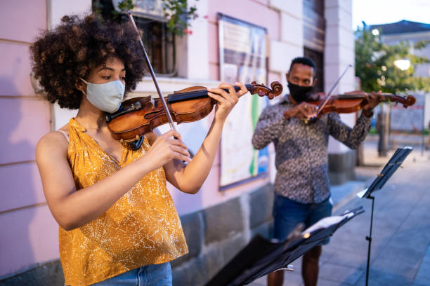 istock Street Afro musicians playing violin and wearing protective face mask, during COVID-19 1268398295