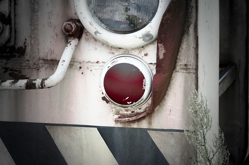 Detailed view of an old, scrap-ripe railroad car with one white and one red light