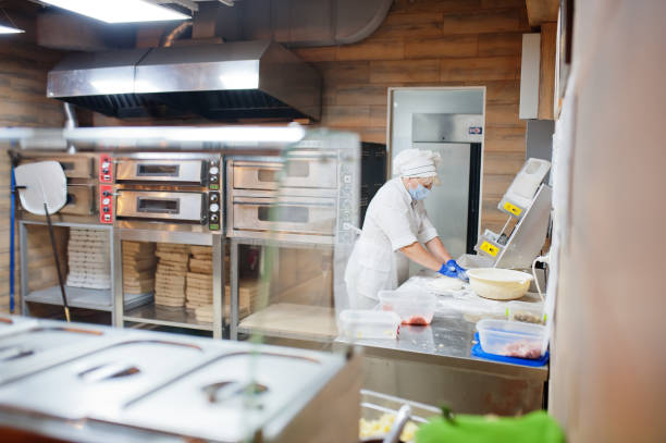 istock Pizza maker in protective mask working in the pizzeria. 1268406096