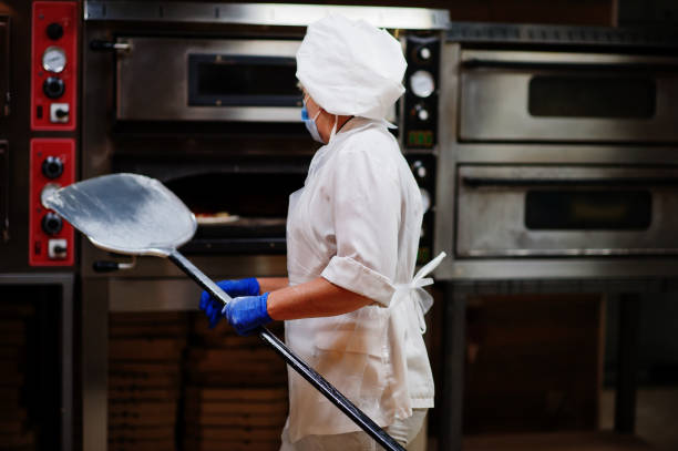 istock Pizza maker in protective mask working in the pizzeria. 1268406117
