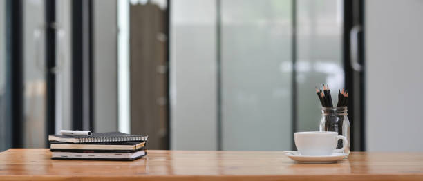 istock Workspace coffee cup and pencil holder are putting on desk surrounded by a stack of books and a pen. 1268406773