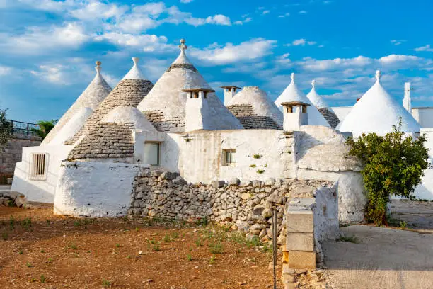 Group of beautiful Trulli, traditional old houses and old stone wall in Puglia, Italy