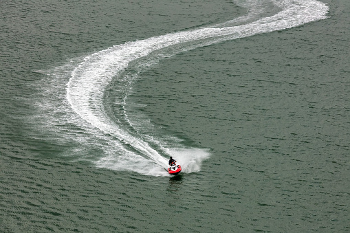 Red jet-ski moving very fast leaving white trace behind it. Sports, competition concept. Aerial view.