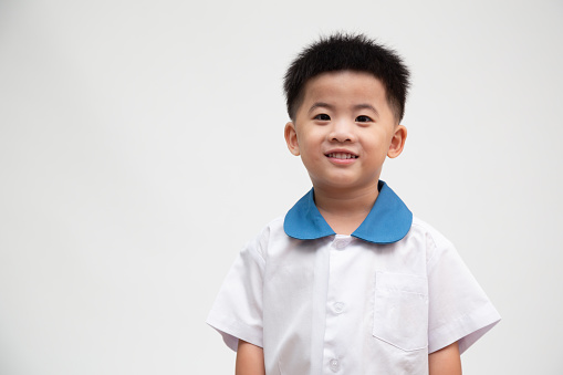 Cheerful smiling asian little boy in student uniform isolated on white background, First day of kindergarten and Back to School concept, Thai boy model