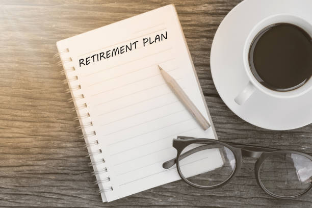 istock Retirement plan word on notebook with glasses, pencil and coffee cup on wooden table. Retirement plan concept. 1268413010