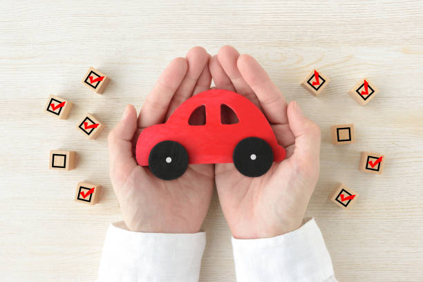 billeks leksak täckt av människans händer omgivna av träblock med kontrollmärken - bilförsäkring bildbanksfoton och bilder