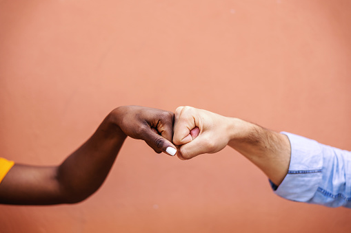 Closeup of multicultural friends giving fist bump to each other.