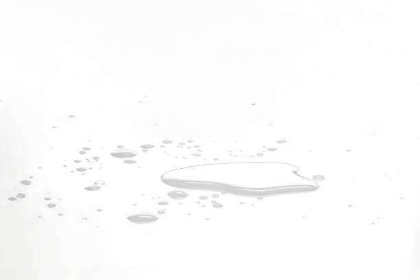Water puddles and droplets on white reflective surface. Frontal view and deep focus.