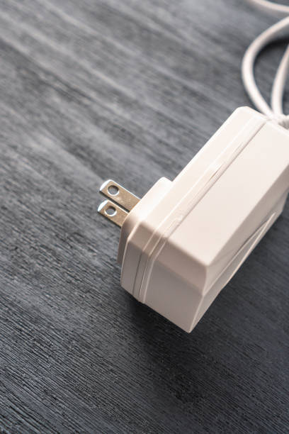 Travel power adapter with US power plug on a wooden background. Electrical concept