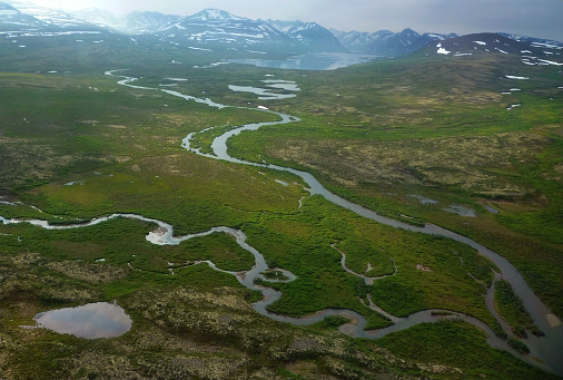 Drone high-angle photo of country road with the beautiful mountain lake surrounded by fresh green peaks by the fjord in Western Noway