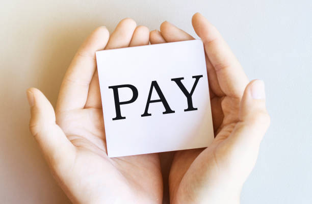 istock white paper with text Pay in male hands on a white background 1268420087