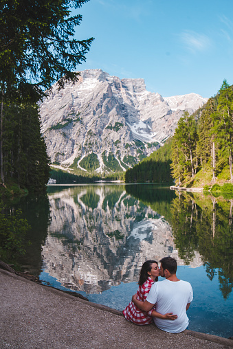 young cute couple sitting on beach looking at mountain lake. copy space