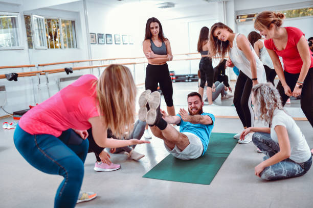 femmine che tormentano il maschio in palestra con esercizi difficili - yoga men male gymnastics foto e immagini stock