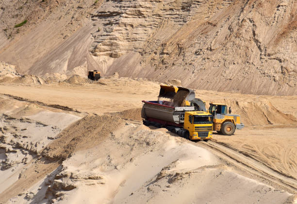 istock Wheel front-end loader loading sand into heavy dump truck at the opencast mining quarry 1268426819
