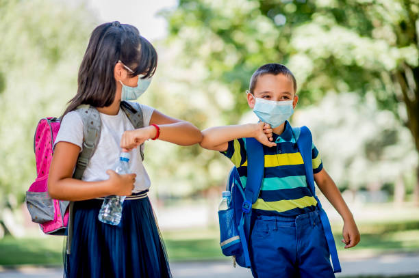Two school children using elbow bump as an alternative handshake outdoors Two school children using elbow bump as an alternative handshake outdoors children only stock pictures, royalty-free photos & images