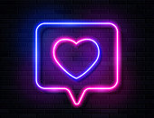 istock Neon Gradient Glowing Heart in Spech Bubble Banner on Dark Empty Grunge Brick Background. 1268428240