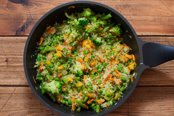 Cooking rice step by step with frozen vegetables, step 4 - adding raw rice, top view, horizontal