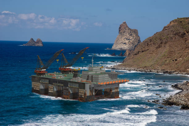 ölplattform durch sturm an felsiger küste angehoben - von starken winden in den meeren bedroht - oil rig sea oil storm stock-fotos und bilder