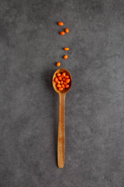 Wooden spoon with sea-buckthorn berries at gray textured background. Wooden spoon with sea-buckthorn berries at gray textured background. Top view, flat lay, concept of ingredients of healthy food autumn copy space rural scene curing stock pictures, royalty-free photos & images