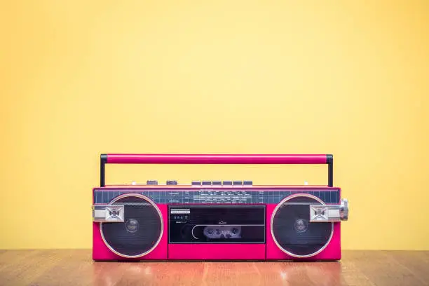 Retro outdated red portable stereo radio cassette recorder from 80s front yellow background. Vintage old style filtered photo