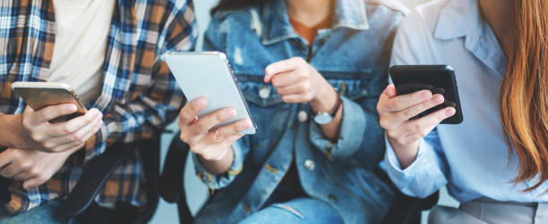istock Group of young people using mobile phone while sitting together 1268435212