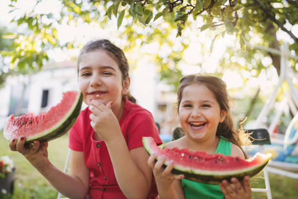 istock Two adorable sisters eat watermelon and make each other laugh 1268437268