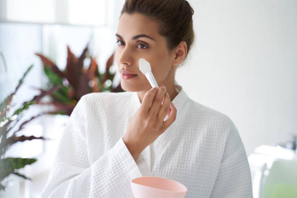 istock Careful lady applying mask on the face with special tool 1268438696