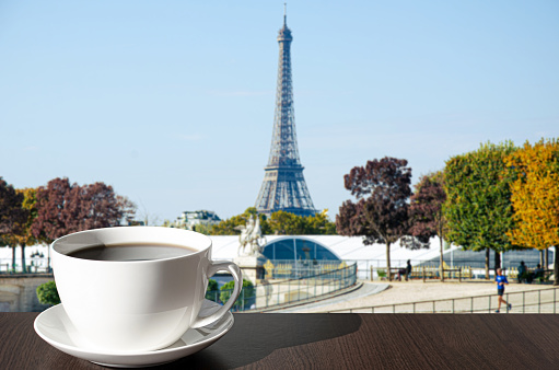 Cup of coffee on the table with view of Eiffel tower in autumn in Paris, France