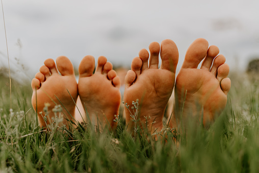 feet of a man and woman. feet of a guy and a girl on the grass. Family picnic in summer in the park on green not mowed grass.