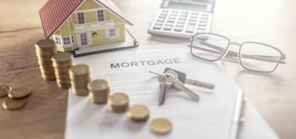 Mortgage contract for the purchase or sale of an apartment house or real estate. Work desk with contract coins model house calculator and pen Mortgage contract for the purchase or sale of an apartment house or real estate. Work desk with contract coins model house calculator and pen. mortgage stock pictures, royalty-free photos & images