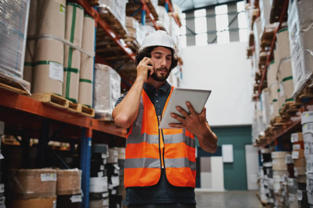 istock Warehouse working holding digital tablet while talking over mobile phone in warehouse 1268447274
