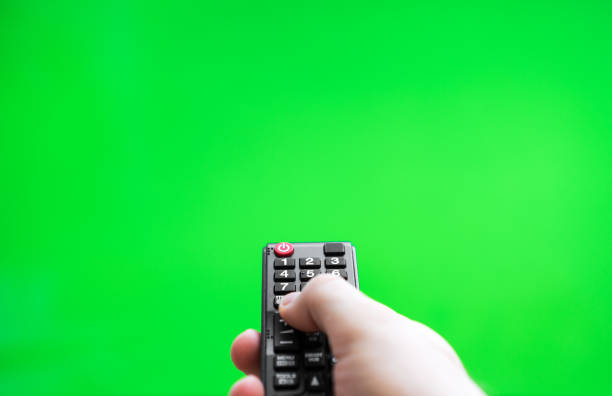 istock Male hand with TV remote control over green screen. Place for your advertisement. 1268448327
