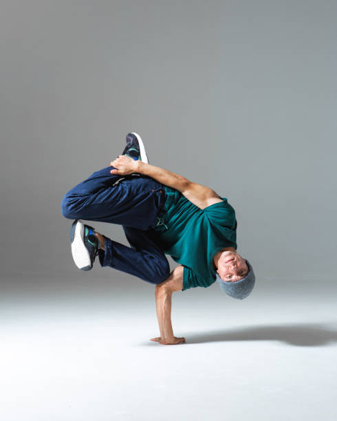istock Stylish b-boy dancing on the floor in studio isolated on gray background. Breakdancing school poster 1268452280