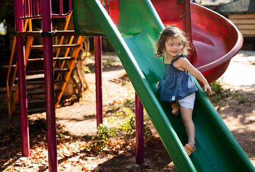 Cute little girl playing on slide at park.