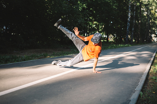 Young guy breakdancer dancing breakdance on the road in the park in summertime. Breakdancing school poster. High quality photo