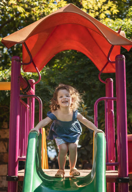 istock Cute little girl playing on slide at park. 1268453092